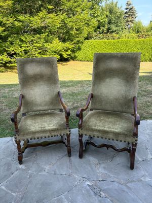 une paire de chaises rembourrées anciennes sur une terrasse en pierre, avec des arbres en arrière-plan