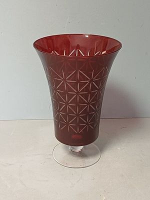 un vase en verre rouge posé sur une table blanche