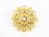 Gros plan sur une broche en or ornée de perles