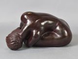 sculpture of a woman laying on her back with her head on the ground