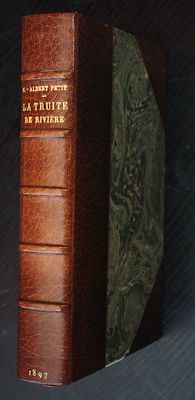 leather bound book sitting on top of a black table next to a clock