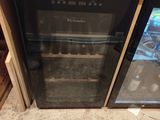 a small refrigerator with a glass door in the middle of a kitchen