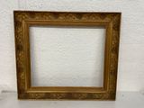 a gold picture frame with a white wall behind it