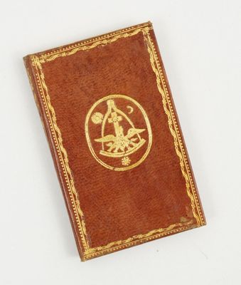 un vieux livre orné d'un emblème doré posé sur une surface blanche