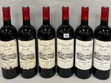 six bottles of red wine lined up in a row on a table