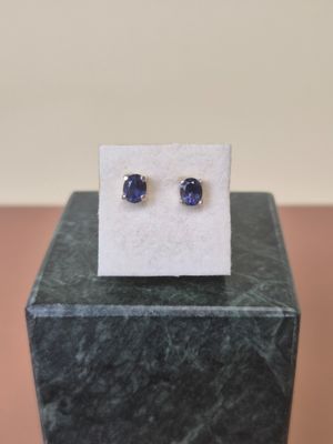 a close up of a pair of blue sapphire earrings on a marble block
