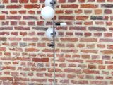 une lampe posée sur un pied devant un mur de briques