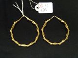 deux paires de boucles d'oreilles créoles en or avec un fil torsadé sur fond noir