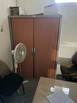 un bureau avec un ventilateur et une chaise dans une pièce
