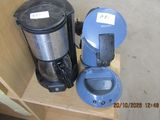 a blue coffee maker and a black coffee pot on a wooden shelf