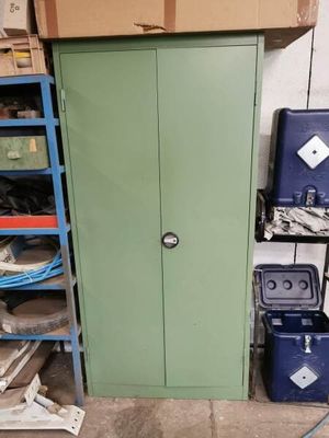 une armoire verte au milieu d'une pièce remplie de cartons