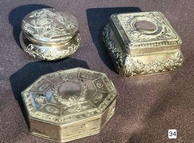 three silver boxes sitting on a table with a brown cloth
