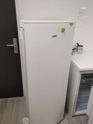 un réfrigérateur blanc dans un coin de la cuisine, à côté d'un plan de travail