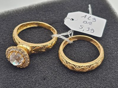 pair of gold tone rings with clear crystal stones on top of a black cloth