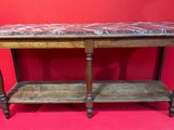 une vieille table en bois avec un plateau en marbre sur fond rouge