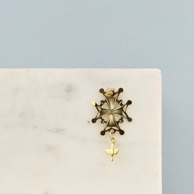 La boucle d'oreille en forme de flocon de neige doré repose sur une plaque de marbre blanc