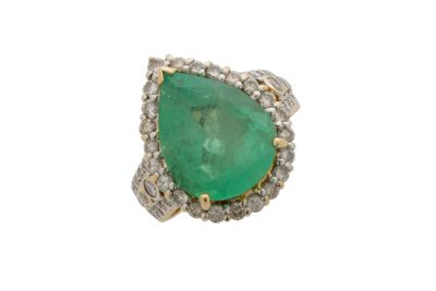 gros plan d'une bague avec une pierre verte entourée de diamants