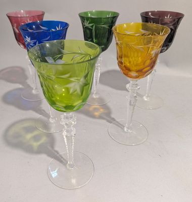 quatre verres à vin de couleurs différentes posés sur une table blanche