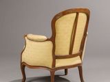 an old chair with a yellow upholstered back and a wooden frame