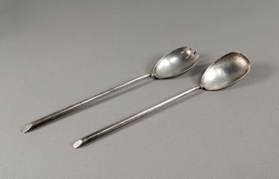 deux cuillères en argent posées sur une table l'une à côté de l'autre