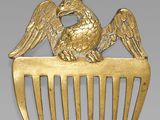 gold plated comb with a bird on top of it and a cross on the side