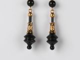 une paire de boucles d'oreilles noires et dorées sur fond blanc