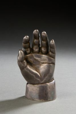 bronze statue of a hand holding a small object on a white surface
