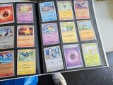 a person holding a book with a lot of pokemon cards on it