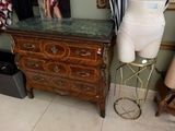 un mannequin posé sur un socle à côté d'une commode