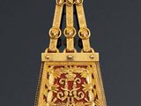 a close up of a gold and red pendant on a black background