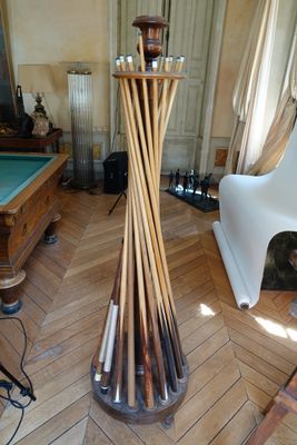 un grand lampadaire en bois au milieu d'une pièce où se trouvent une table de billard et une table de billard