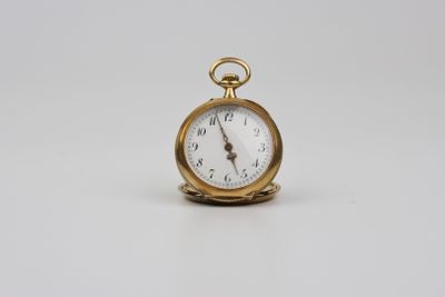 une image représentant une petite montre de poche en or posée sur une surface blanche