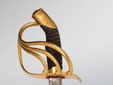 a close up of a sword with a gold handle on a gray background