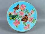 une assiette bleue décorée d'un papillon et de fleurs