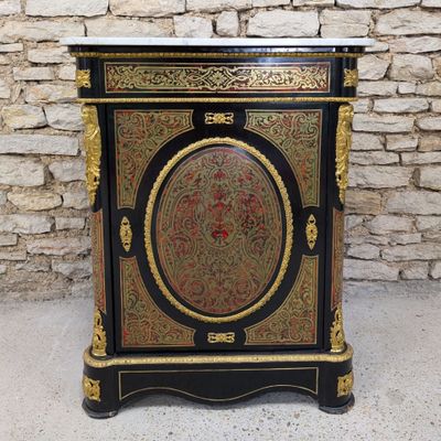 a black and gold painted cabinet sitting in front of a brick wall