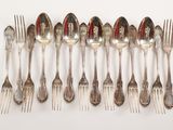 many spoons and forks arranged in a row on a table