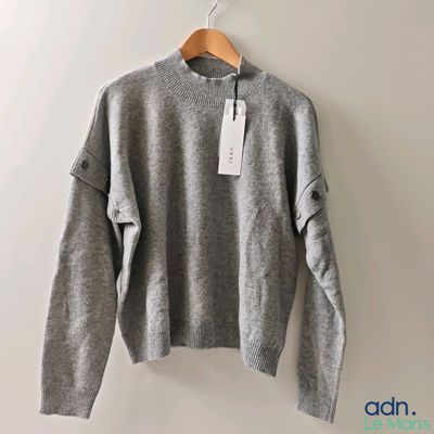 the sweater is hanging on a hanger on the wall