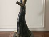 a statue of a woman holding a book on top of a dresser