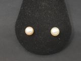 a pair of pearl earrings on a black display case