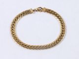 a close up of a gold bracelet on a white surface