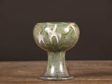 un petit vase vert posé sur une table en bois