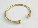 un gros plan d'un bracelet en or orné de deux boules