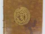 an old book sitting on a white surface with a gold cover