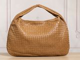 a brown woven bag sitting on top of a wooden table
