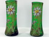 une paire de vases verts ornés de fleurs violettes, posés sur un fond blanc