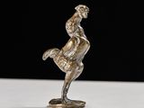 silver figurine of a man riding a horse on a white surface