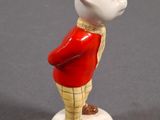 a small figurine of a teddy bear wearing a red coat