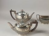 three pieces of silver tea and coffee set on a white surface