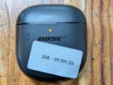 des AirPods noirs posés sur une table en bois sur laquelle est collée une étiquette