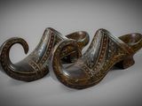 pair of wooden shoes with carved designs on them on a gray surface